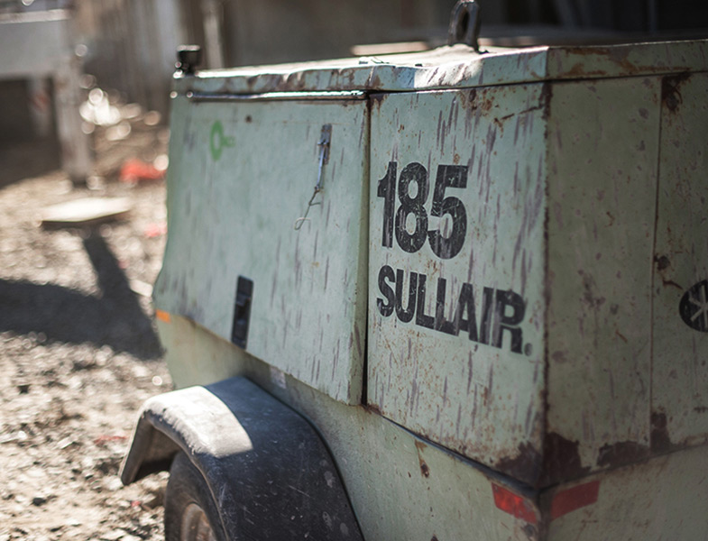 A Sullair 185 air compressor on a job site